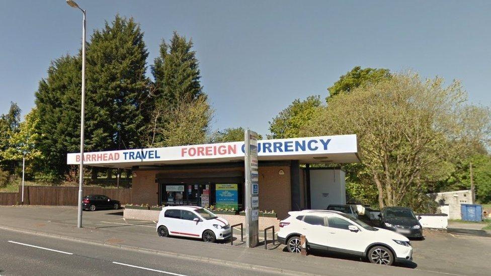 A petrol station with several cars in front of it and Barrhead Travel and Foreign Currency being advertised as available within it