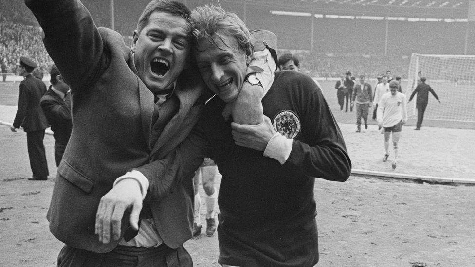 Denis Law, in a Scotland shirt, is hugged by a cheering man in a suit as he leaves the pitch at Wembley