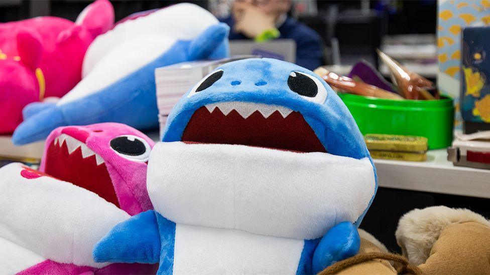 Soft toys of the Baby Shark characters, including a blue and white shark and a pink and white shark.