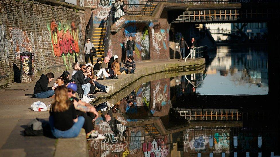 People by a canal in the sun