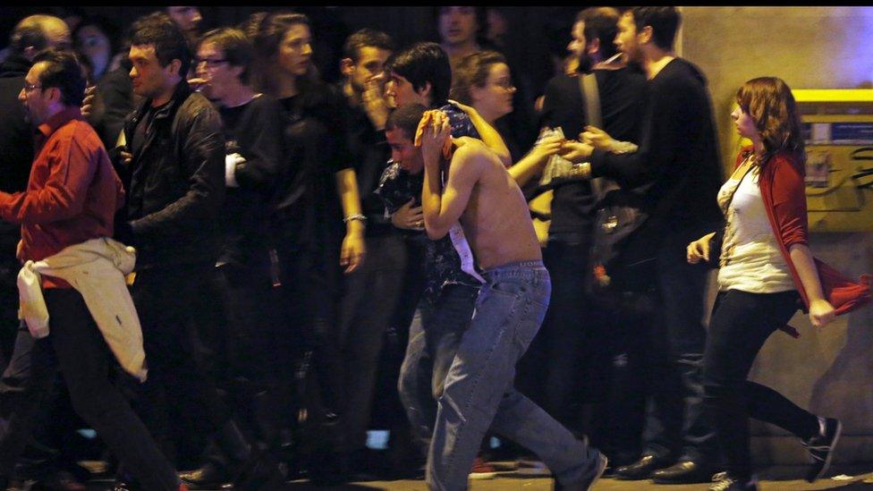 An injured man holds his head as people gather near the Bataclan concert hall following fatal shootings in Paris, France, November 13, 2015