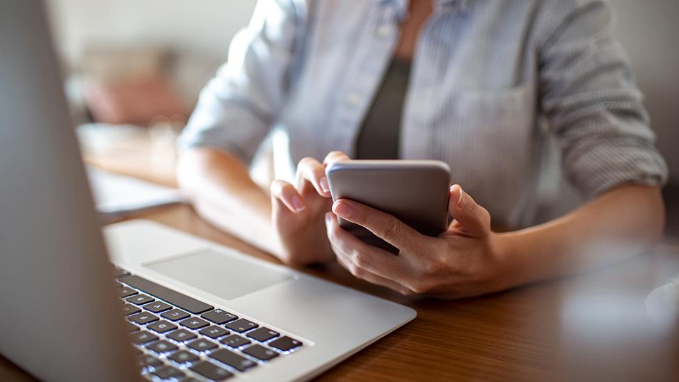 Woman using phone and laptop