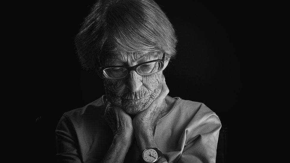 Brunhilde Pomsel, in black and white still from the documentary, hold the sides of her neck, looking down