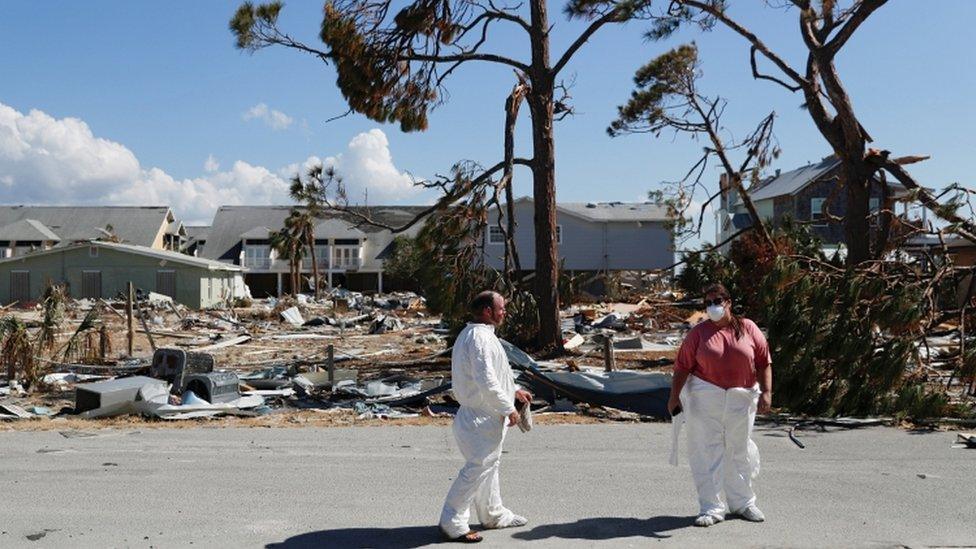 Mark MacEntyre, 38, of Headland, AL, and Lindsey Crawson, 37, of Birmingham, AL, wear equipment to protect themselves from mold while taking a break from cleaning a house damaged by Hurricane Michael