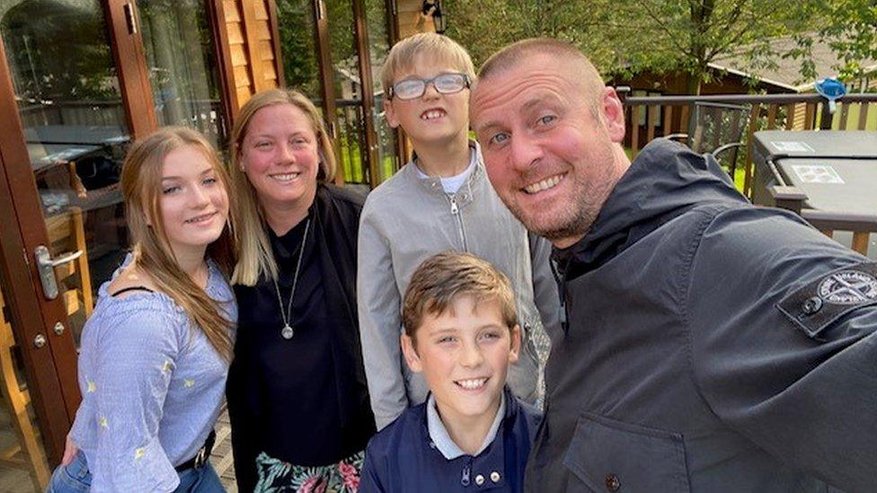 A family of five smiles at the camera