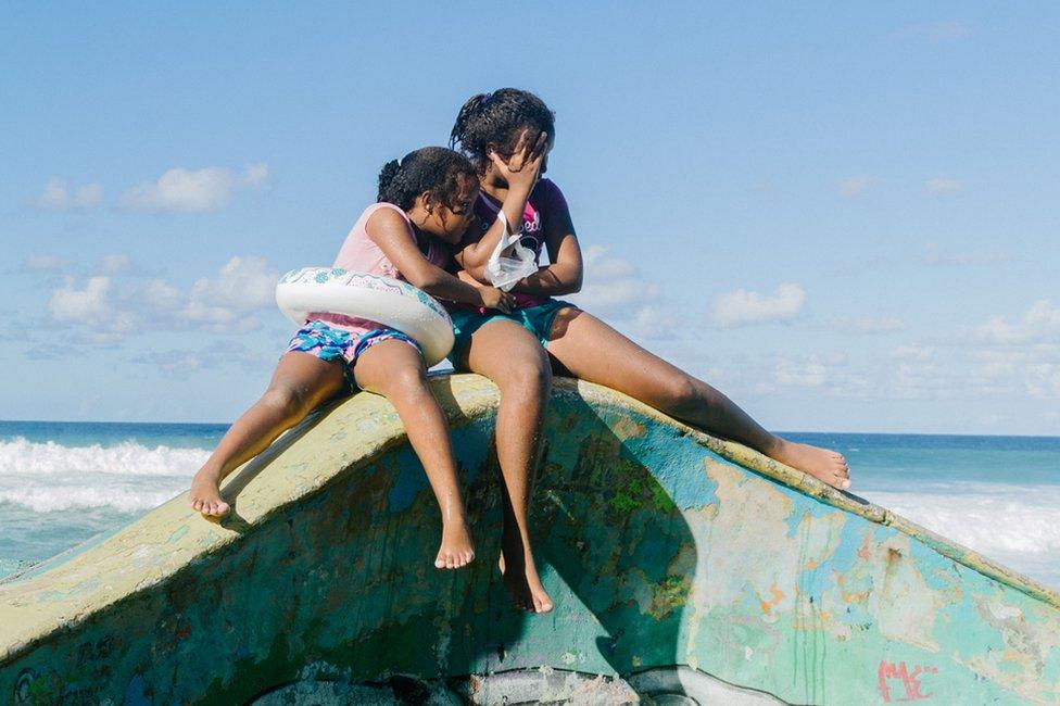 Two young girls pose for a photo on the edge of a pool