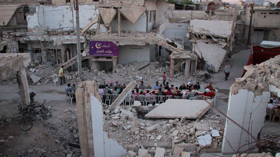 Syrian residents of the rebel-held town of Douma, on the outskirts of the capital Damascus, break their fast with the "iftar" meal on a heavily damaged street on June 18, 2017, during the Muslim holy month of Ramadan.