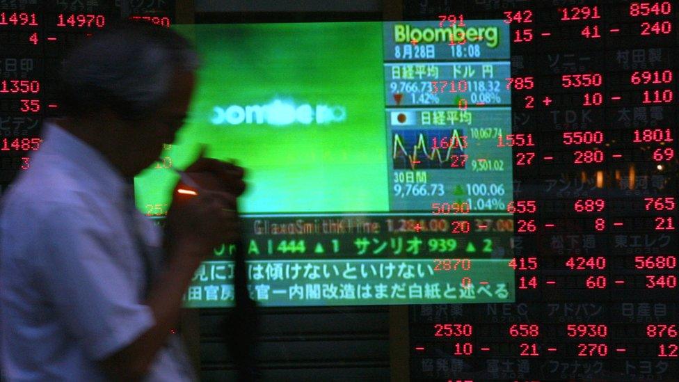 Man lighting up in front of stock market board