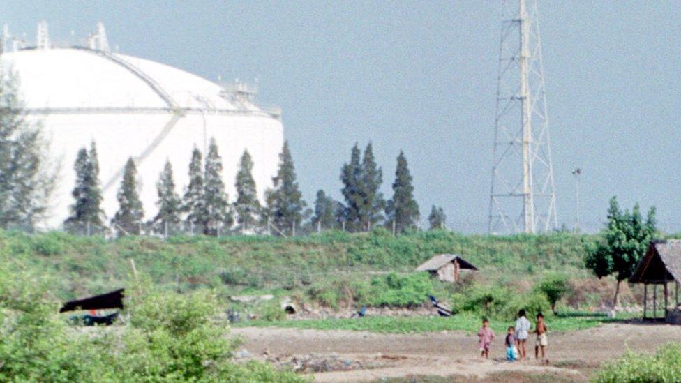 File picture 18 February 2001 shows Acehnese children in a field at Ujong Blang village, Lhokseumawe, Aceh province, in front of holding tanks at the PT Arun liquefied natural gas facility owned by ExxonMobil