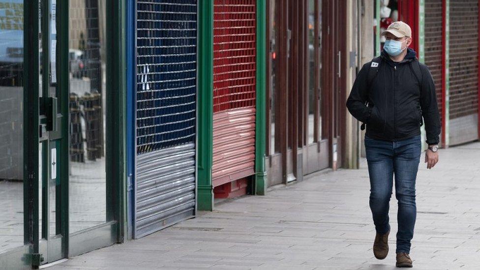 man-walking-past-closed-shops.