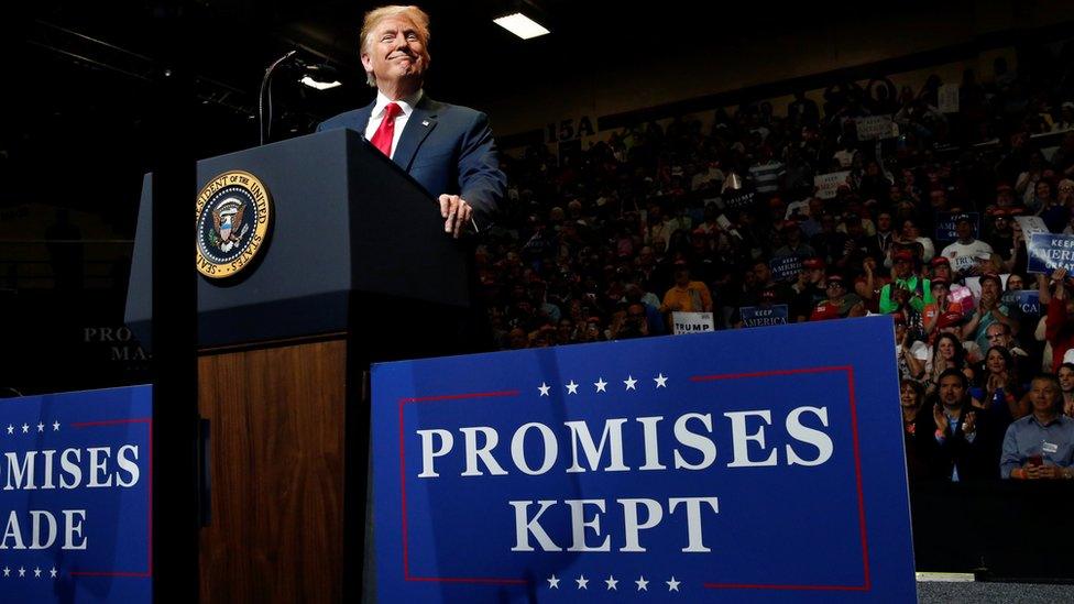 U.S. President Donald Trump smiles at a rally with supporters next to a sign reading "Promises Kept" at North Side middle school in Elkhart, Indiana, U.S. on 10 May 2018