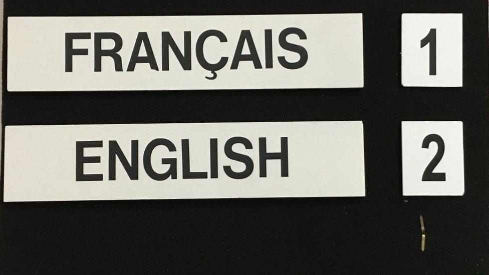 placard informing reporters with headsets which channels they should choose to hear English and French translations