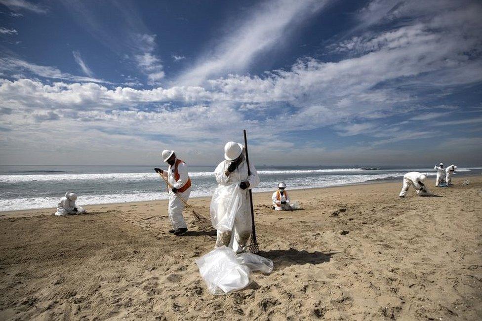 Crews pick the tar from the beach after an oil spill off the coast of Huntington Beach, California, USA, on 4 October 2021