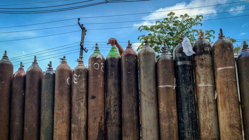 People wait to fill up empty oxygen canisters outside a factory in Yangon, amid a surge in the number of Covid-19 coronavirus cases.