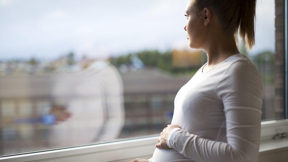 Pregnant woman gazing out of a window