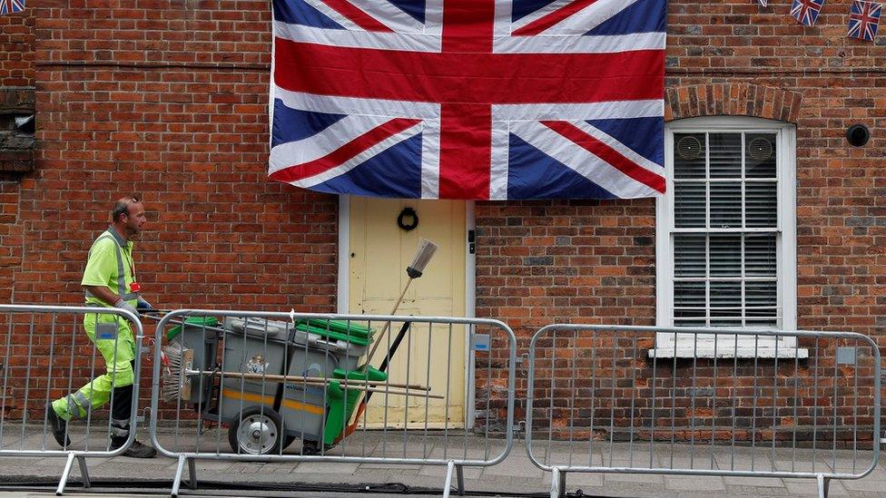 A street cleaner walks past a house decorated in bunting and a Union flag in Windsor