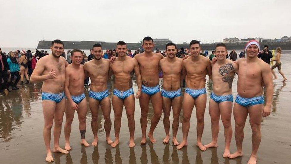 A group of men in trunks on the beach