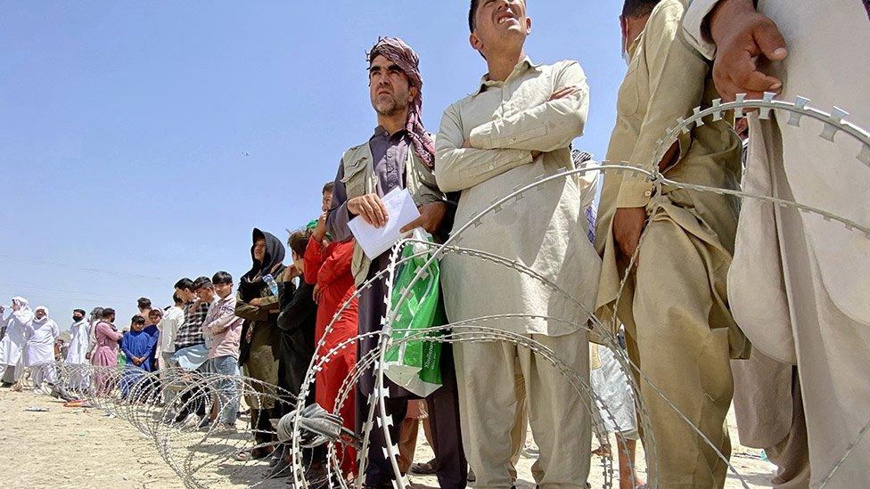 Afghans including those who worked for the US, NATO, Europe Union and the United Nations in Afghanistan wait outside the Hamid Karzai International Airport to flee the country