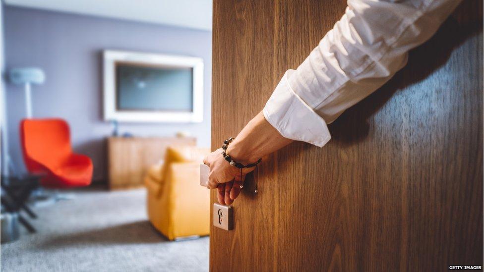 Hand holding hotel room door open