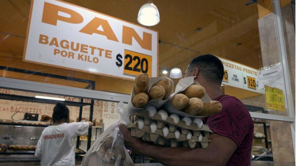 A man buying baguettes for 220 Pesos each