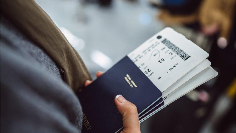 A woman holds passports and boarding passes