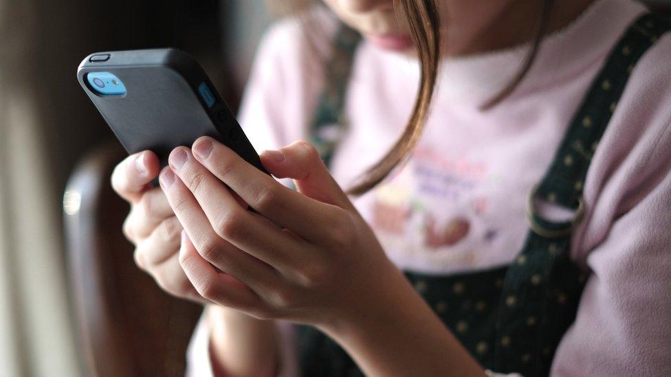 Child with smartphone in hand.