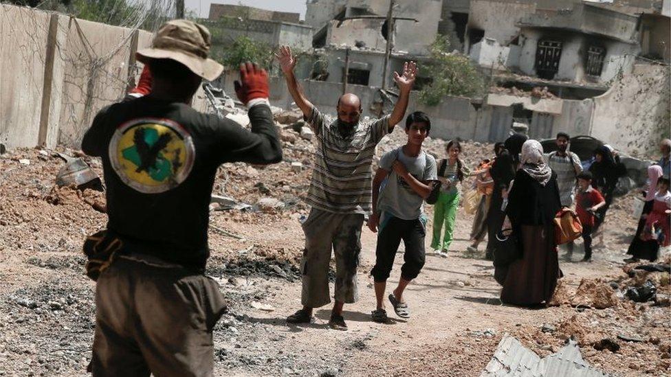 Iraqi man holds his hands up for a security check in Mosul (June 2017)