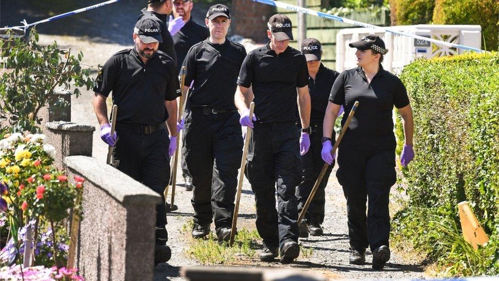 Police forensic officers search a garden