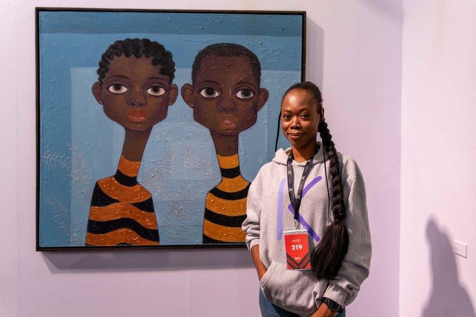 Alduphina Imuede, an artist represented by Pacers Gallery, poses for a portrait in front of her work.