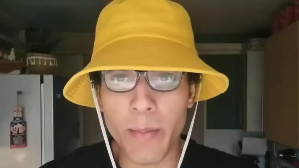Nicholas Prosper seen wearing a yellow bucket hat.