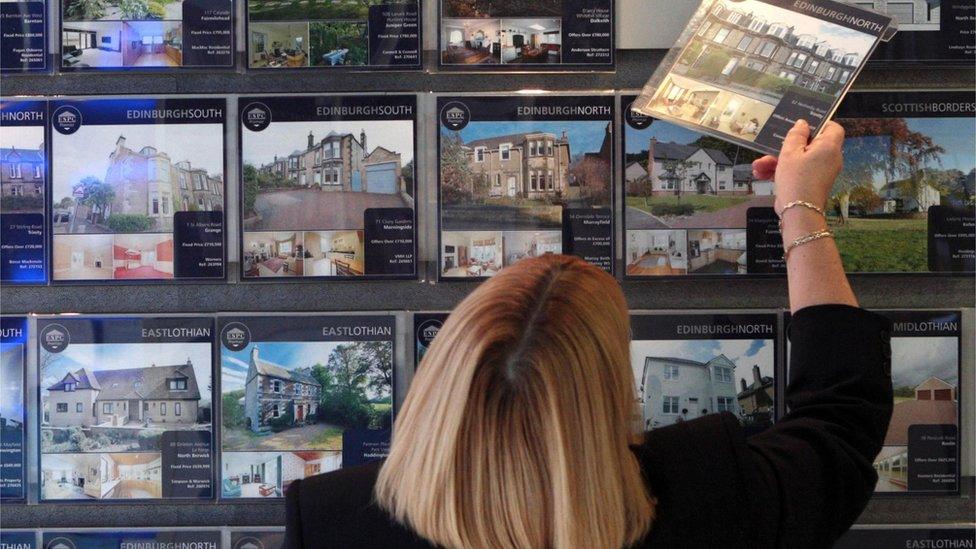 woman looks in estate agent window