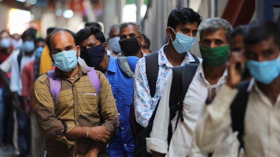 Passengers wearing protective face masks stand in a queue on a platform to get tested for the coronavirus disease (COVID-19), at a railway station, in New Delhi, India, October 5, 2020.