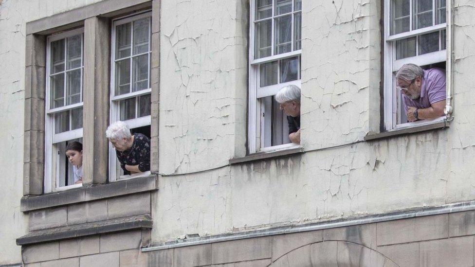 People lean out of windows to see the funeral procession go past in Edinburgh.