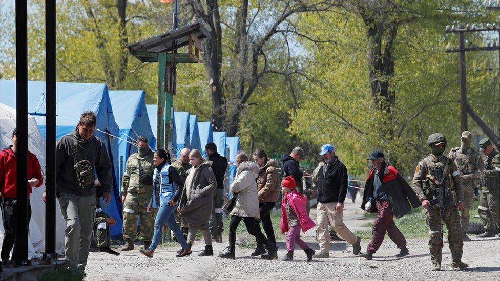 Civilians who left the area near Azovstal steel plant in Mariupol walk accompanied by UN staff