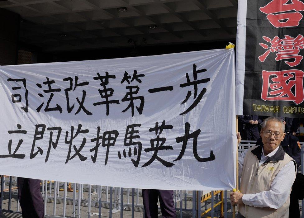 This picture taken on January 10, 2017 shows a pro-Taiwan independence activist displaying a banner that reads "First step to reform, put Ma Ying-jeou in custody" outside the Taipei District Court.