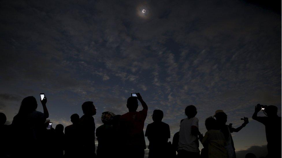 People taking pictures of the eclipse with their phones, on Ternate island, Indonesia