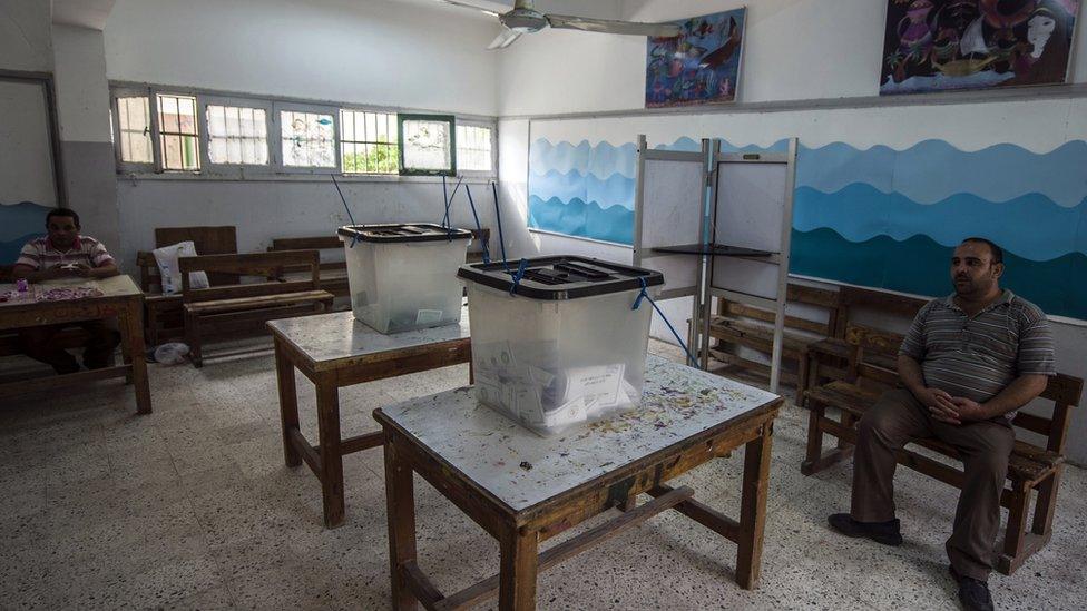 Egyptian officials sit in an empty polling station in Cairo's Giza district, on the second day voting in Egypt's parliamentary elections on 19 October 2015.