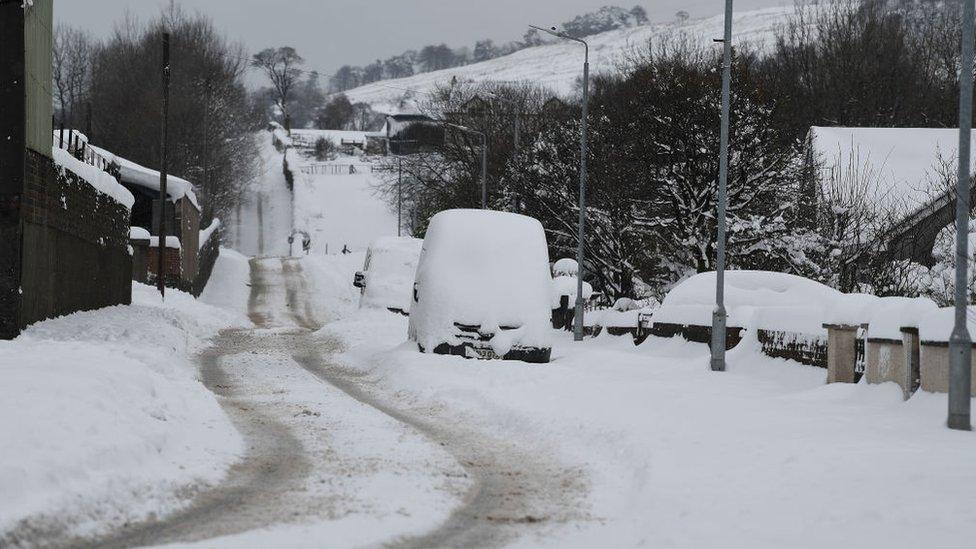 Cars and vans parked up by the side of the road covered in snow on March 1, 2018