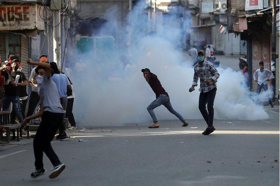 Demonstrators throw stones towards Indian police amidst tear gas smoke fired by police during a protest ahead of the sentencing of Yasin Malik near his residence in Srinagar May 25, 2022