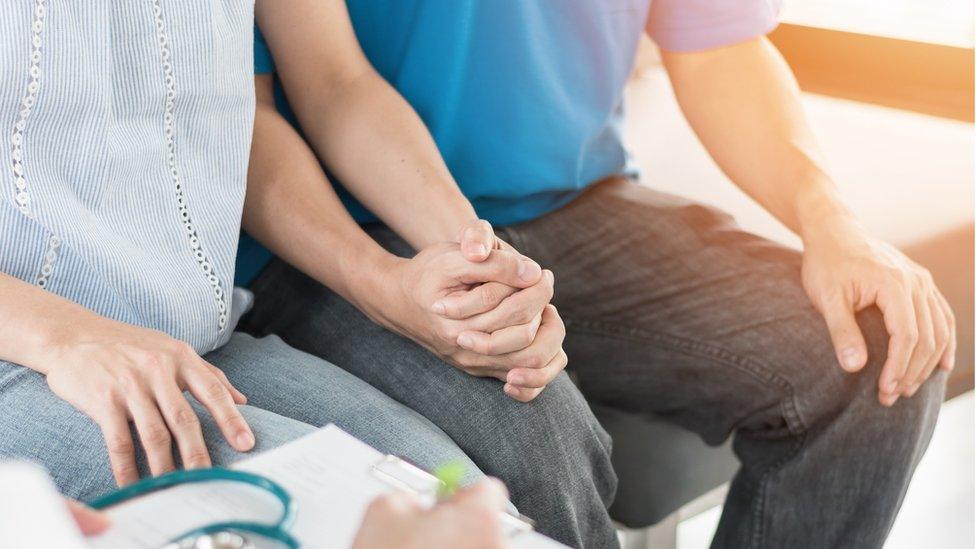 Couple holding hands while meeting a doctor