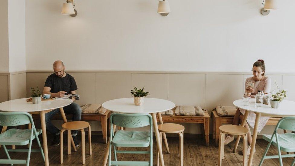 Two customers social distancing in a cafe