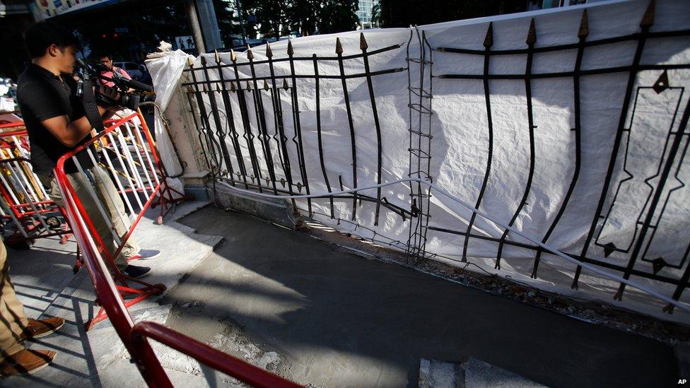 Racks and a tarpaulin block off the bomb crater, now covered with fresh cement, at the Erawan Shrine