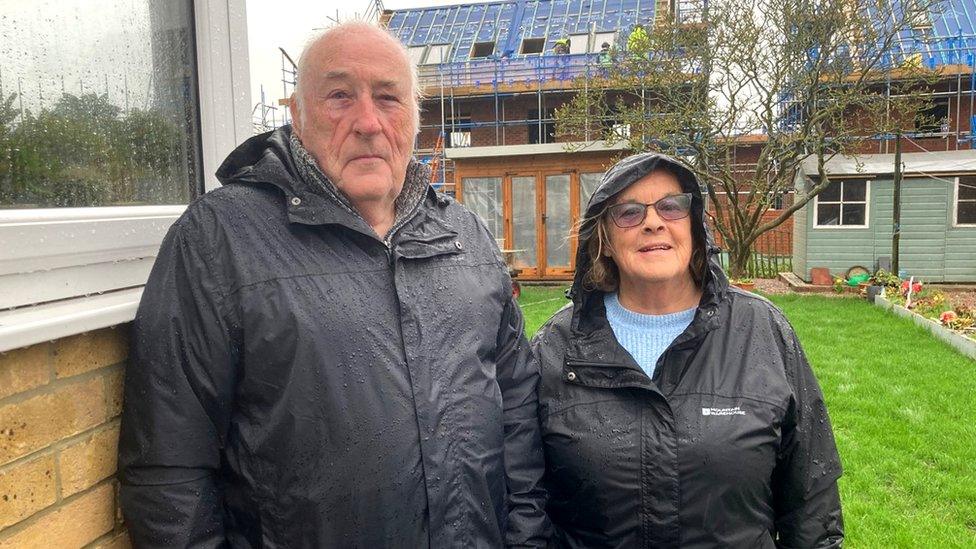 Mr and Mrs King standing in their garden with the new builds behind them