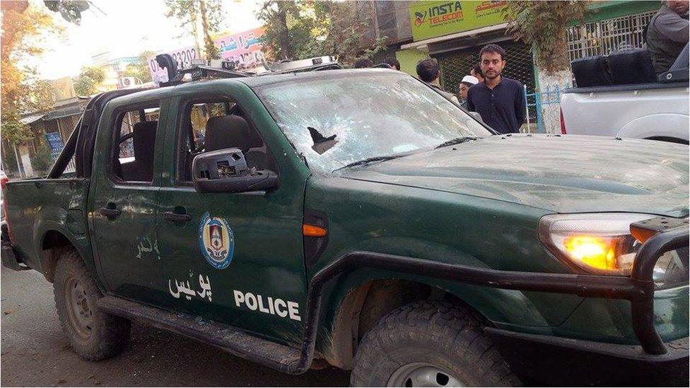 Bystanders look at a damaged Afghan police vehicle