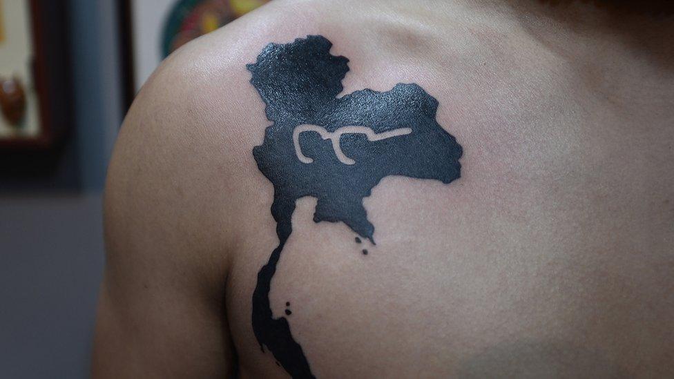 Tattoo on someone's shoulder showing the outline of Thailand with the number 9 in the middle