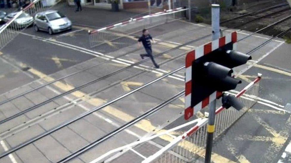 Man running across level crossing