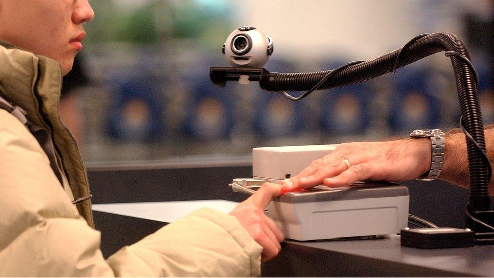 A traveller has his finger scanned at JFK airport