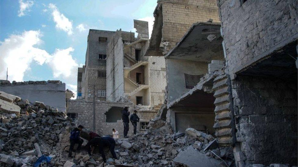 People inspect the rubble after airstrikes, at a marketplace in Areeha town (Jericho town), southern Idlib,