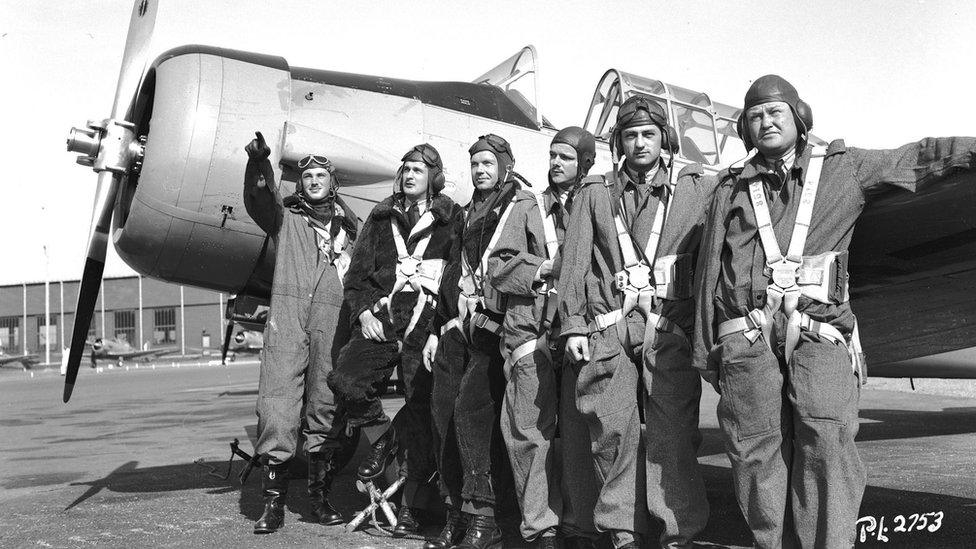 pilots posing next to a fighter plane