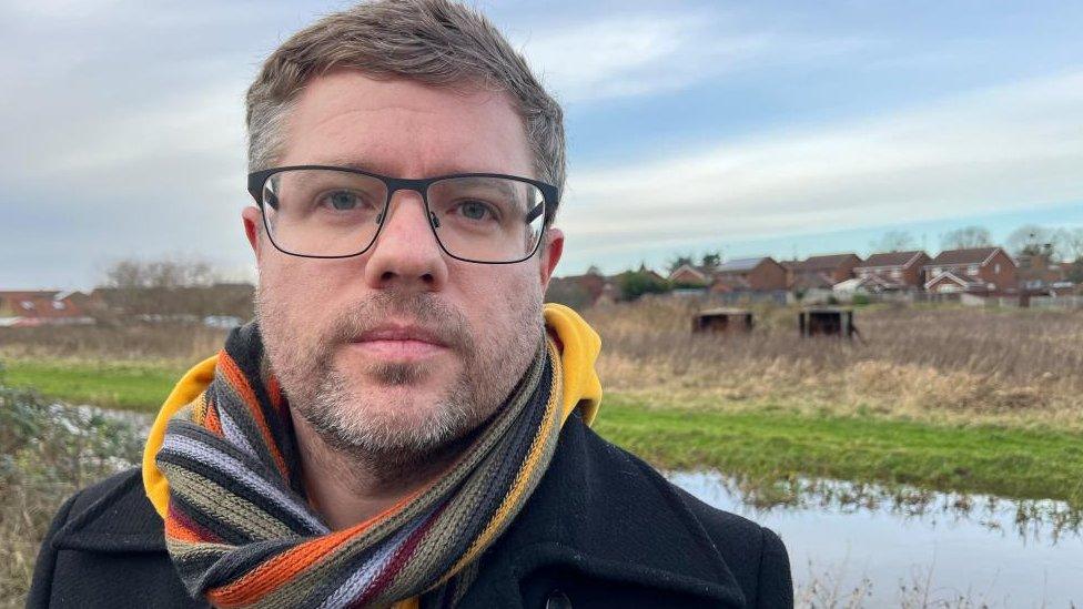 Councillor Rob Colwell standing beside the Gaywood River with Russett's Meadow in the background